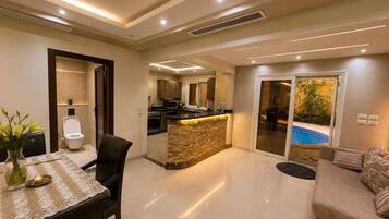 A modern living area with a kitchen, dining space, and a pool view.