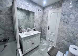 A bathroom with a marble sink, a mirror, a shower, and a toilet. - Sea front apartment in Playa Rocio, Puerto Banus with swimming pool and parking (Marbella)