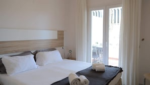 Een hotelkamer met een bed, een hoofdeinde, een raam met gordijnen en uitzicht op een buitenruimte.