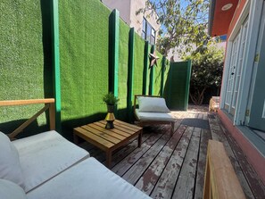 Eine Holzterrasse mit einer Couch, einem kleinen Tisch und einem Stuhl.