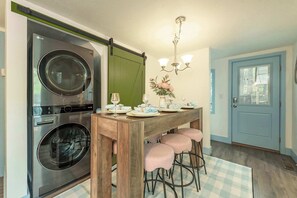Eine kompakte Küche mit integrierter Waschmaschine und Trockner, einem Holztisch mit Barhocker und einer blauen Tür.