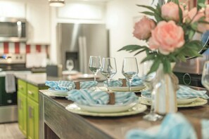 Eine Küchenarbeitsplatte mit Essplatz, einschließlich Tellern, Gläsern und einer Vase mit Blumen.