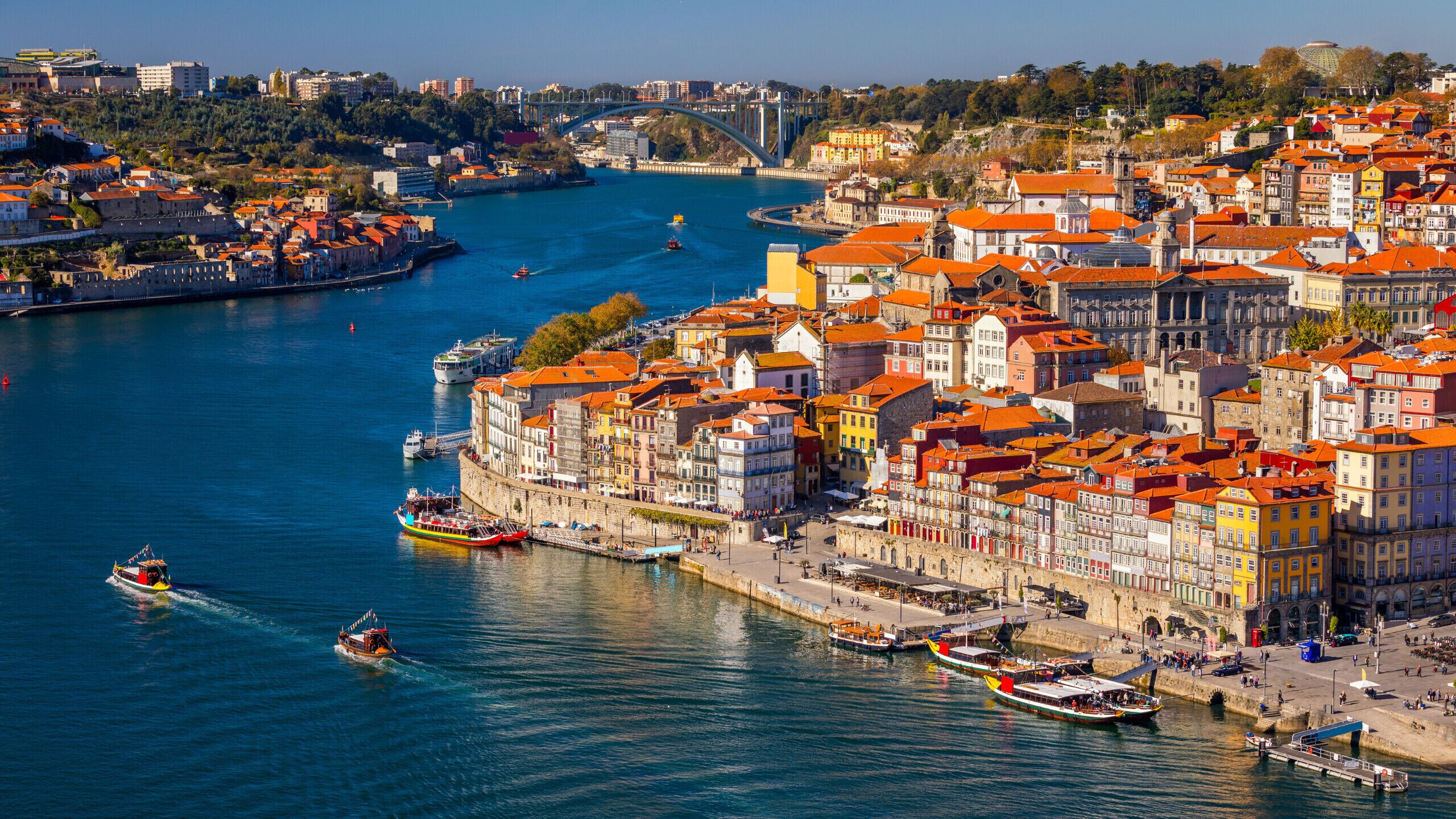 A coastal cityscape with a river, historic buildings, and boats.