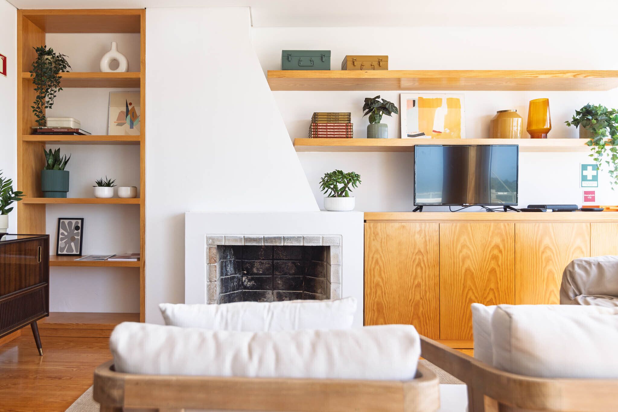 Un salon moderne avec une cheminée, des étagères en bois et un téléviseur.