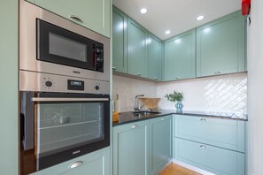 Eine Küche mit Einbauofen, Mikrowelle und Spüle mit modernem Wasserhahn.
