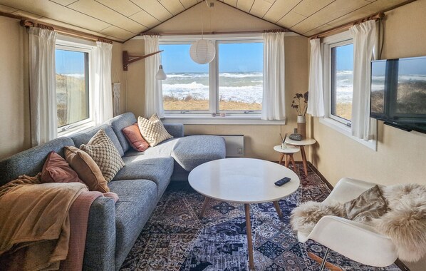 A cozy room with a sofa, a round table, and a view of the sea. - Gorgeous home in Hjørring with house sea view (Hjørring)