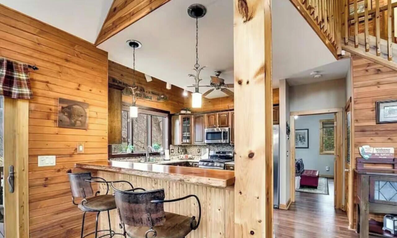 A wooden interior with a kitchen, bar area, and a staircase.