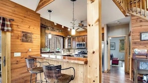 Ambiente in legno con cucina, angolo bar e una scala.
