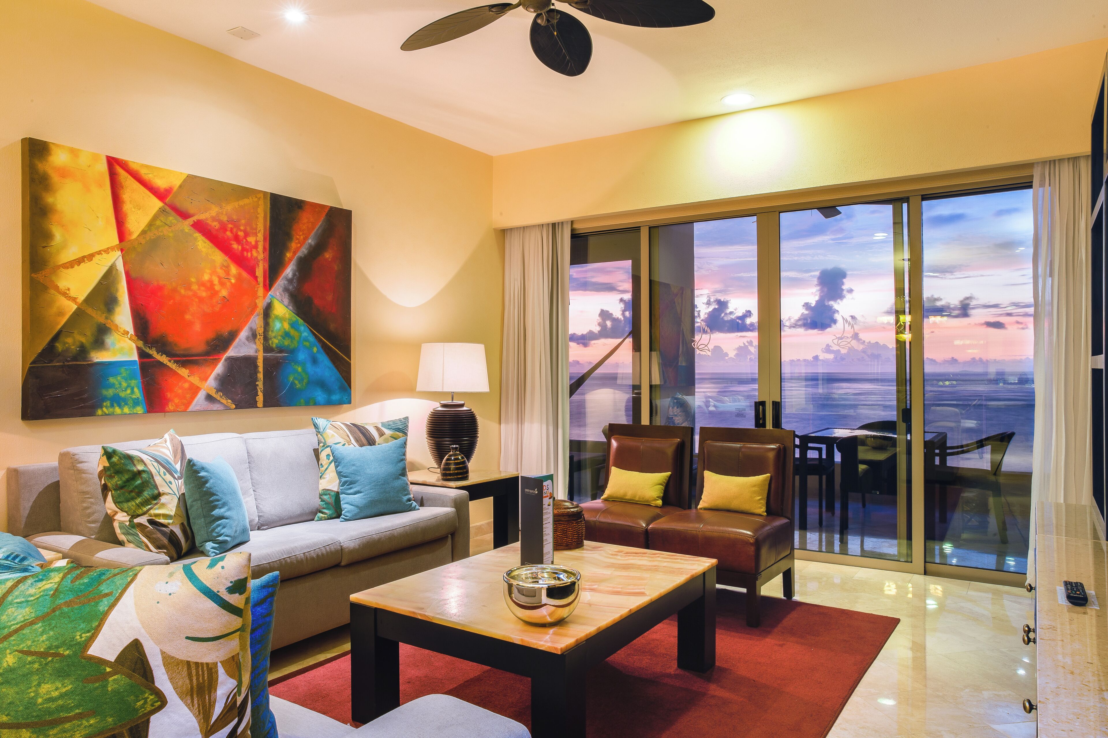 Uma sala de estar moderna com sofá, poltronas, mesa de centro e uma grande pintura abstrata.