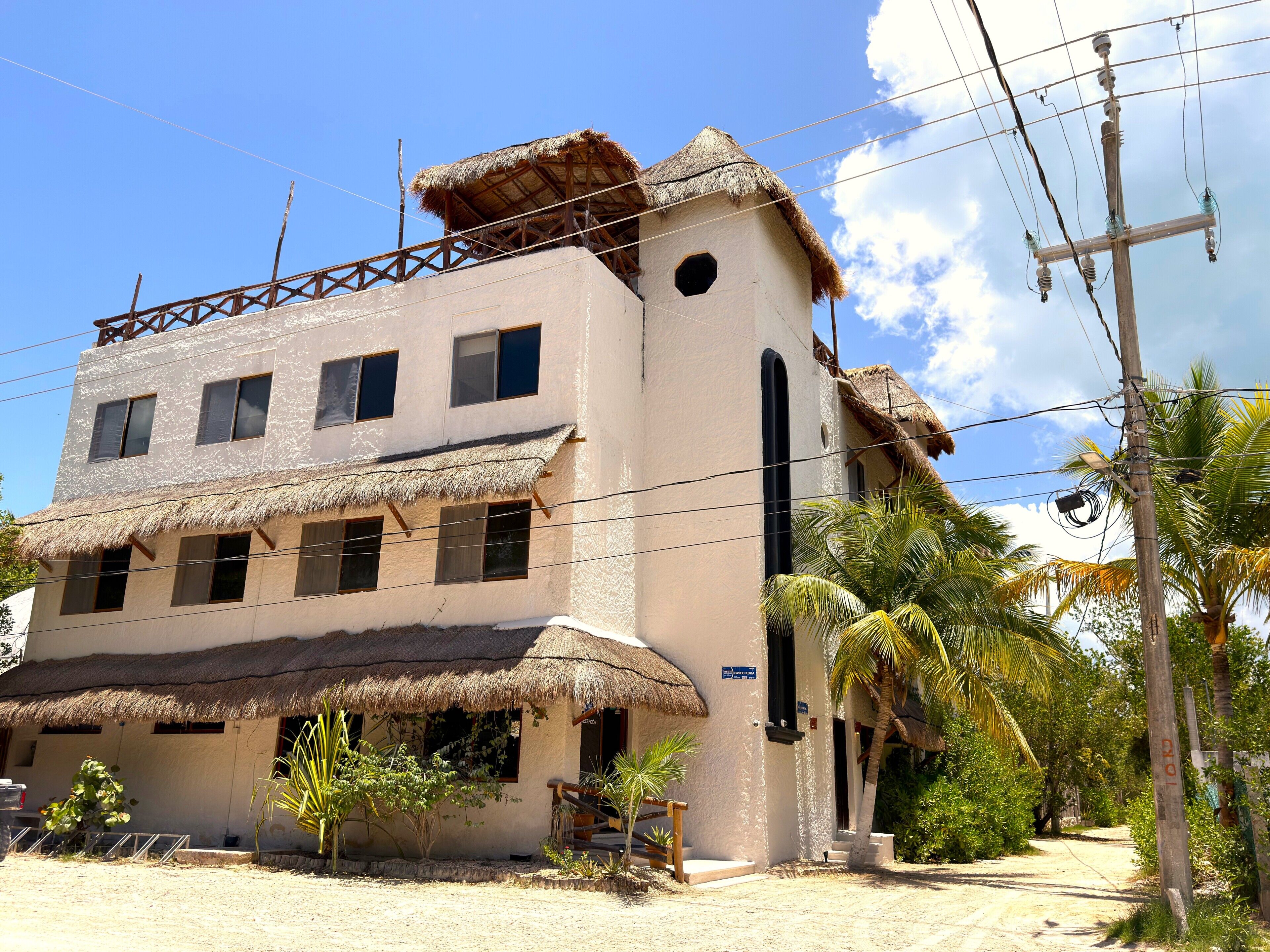 A building with a thatched roof, multiple windows, and a visible staircase leading to the entrance.