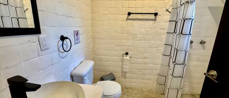 Un baño con lavamanos, inodoro y cortina de ducha blancos.
