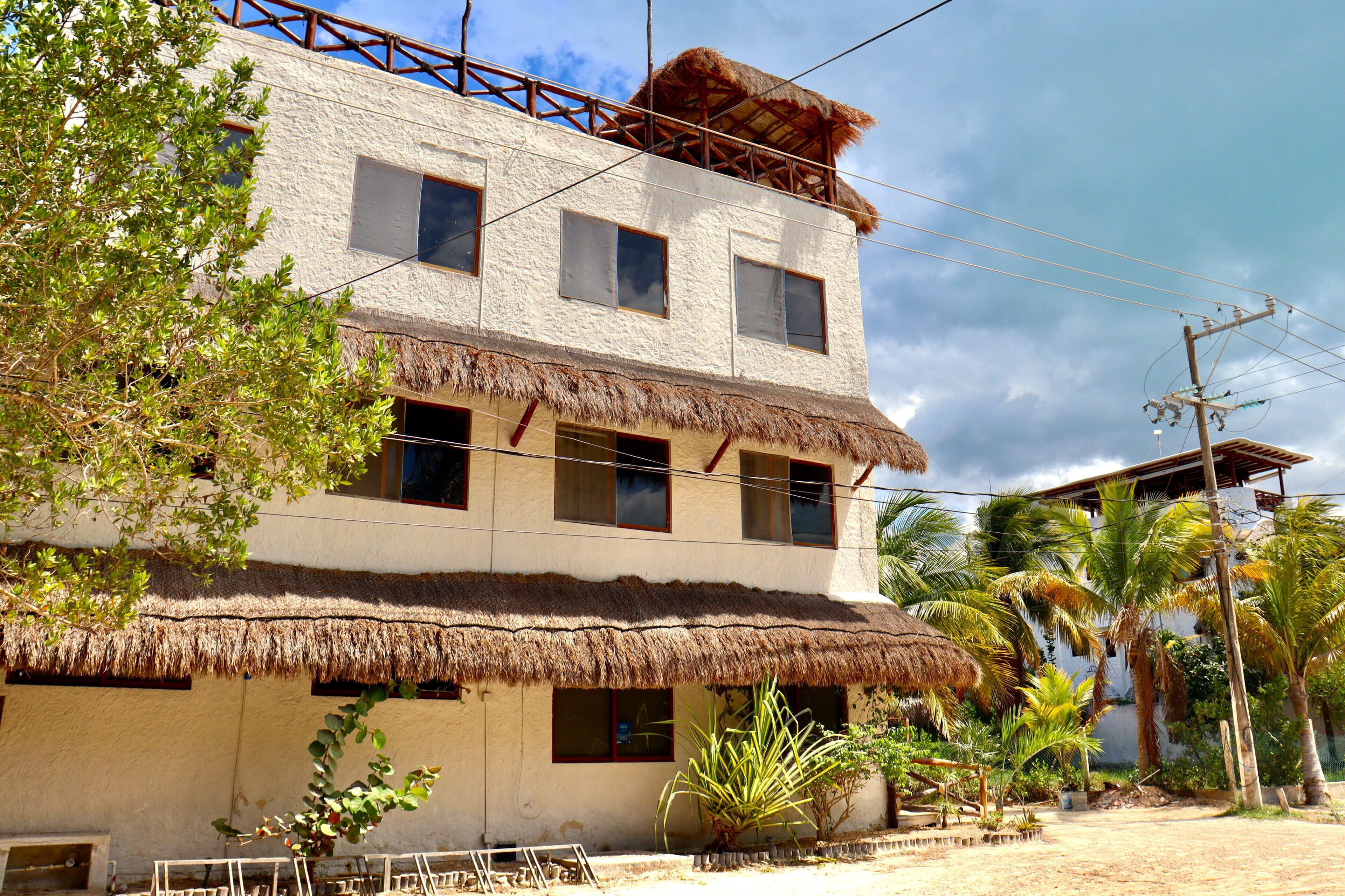 A two-story building with a thatched roof, multiple windows, and a balcony.