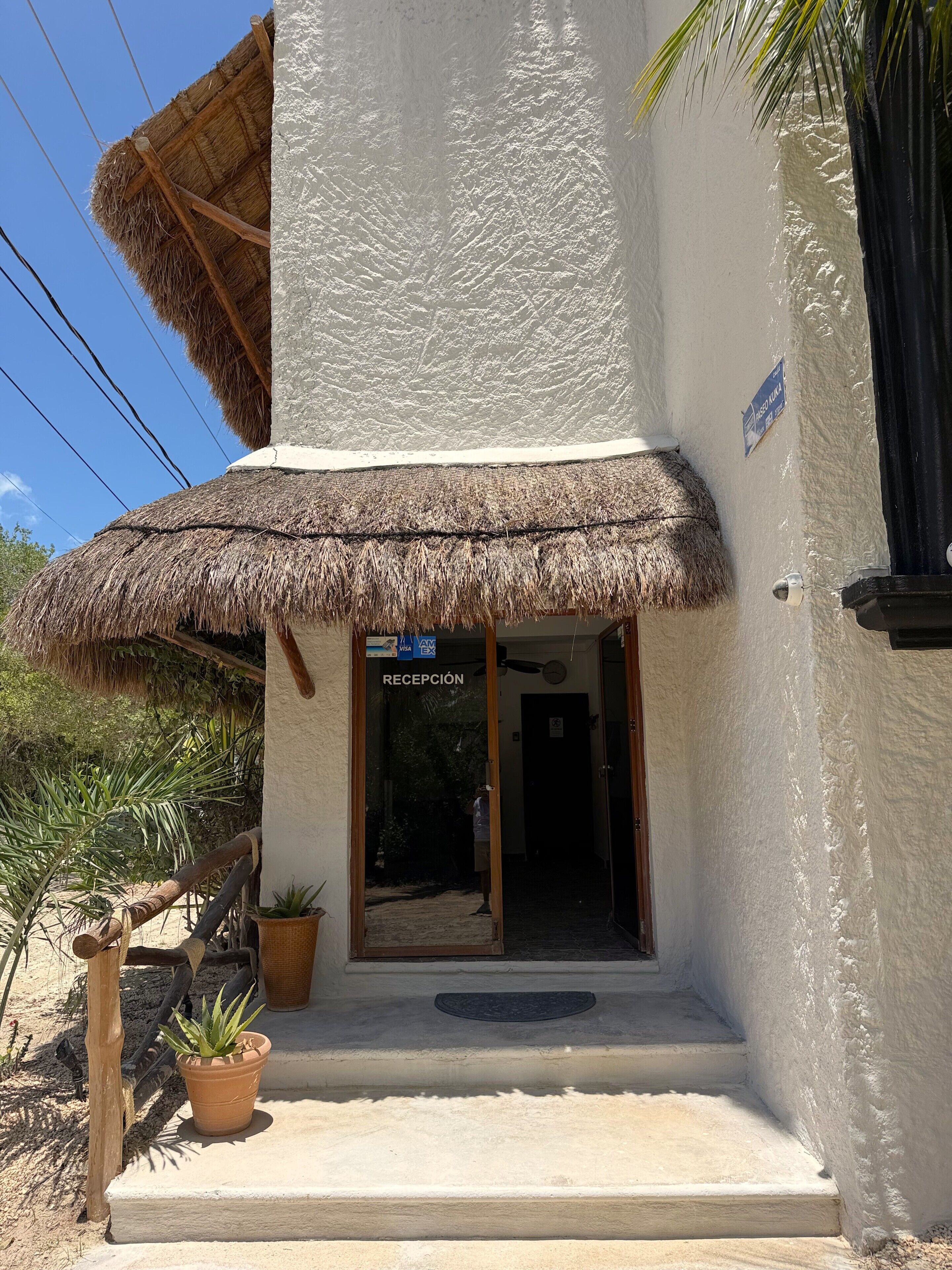 A building with a thatched roof entrance, a reception desk, and a sign indicating a reception area.