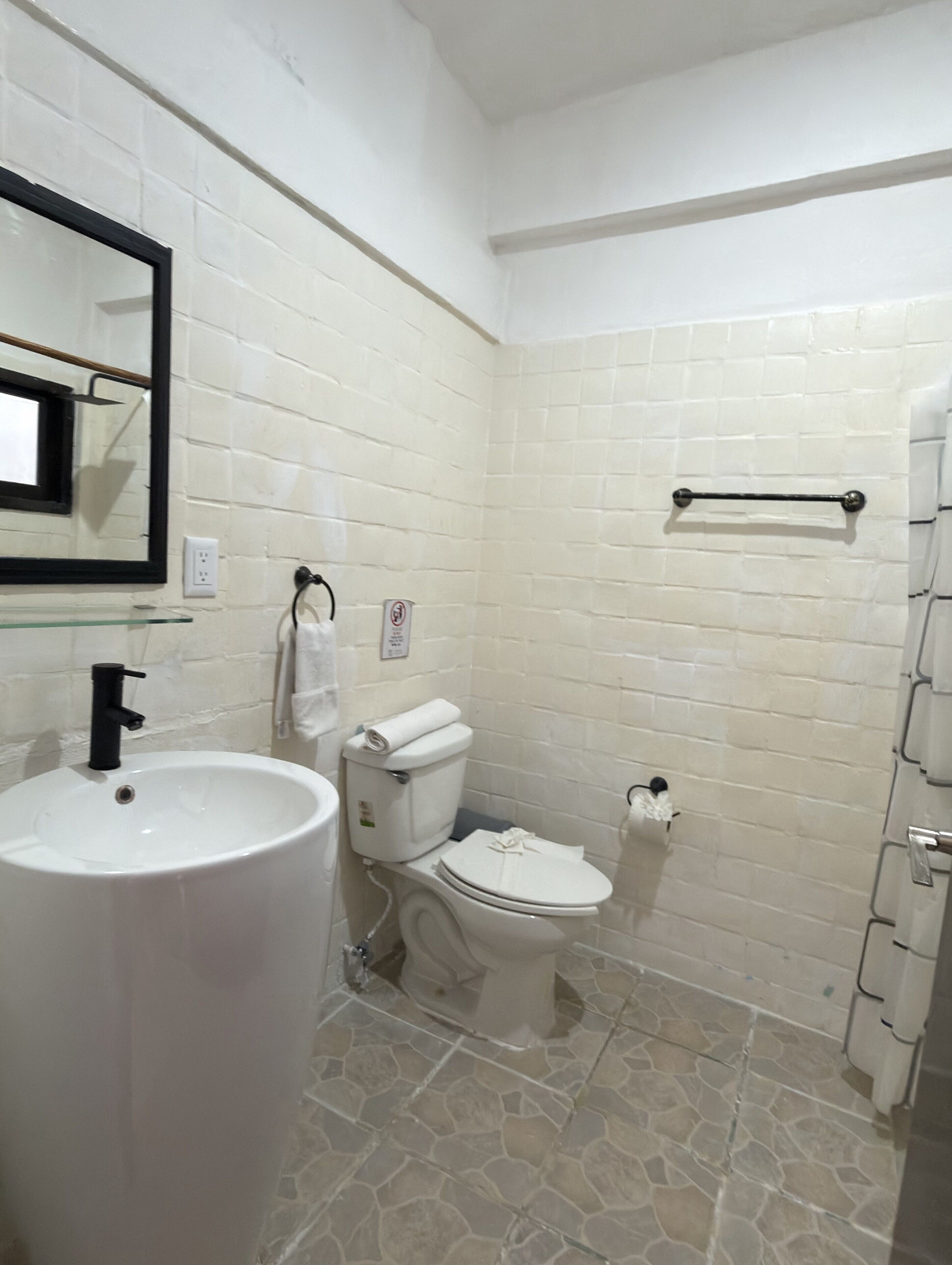 A bathroom with a white sink, toilet, and a mirror.