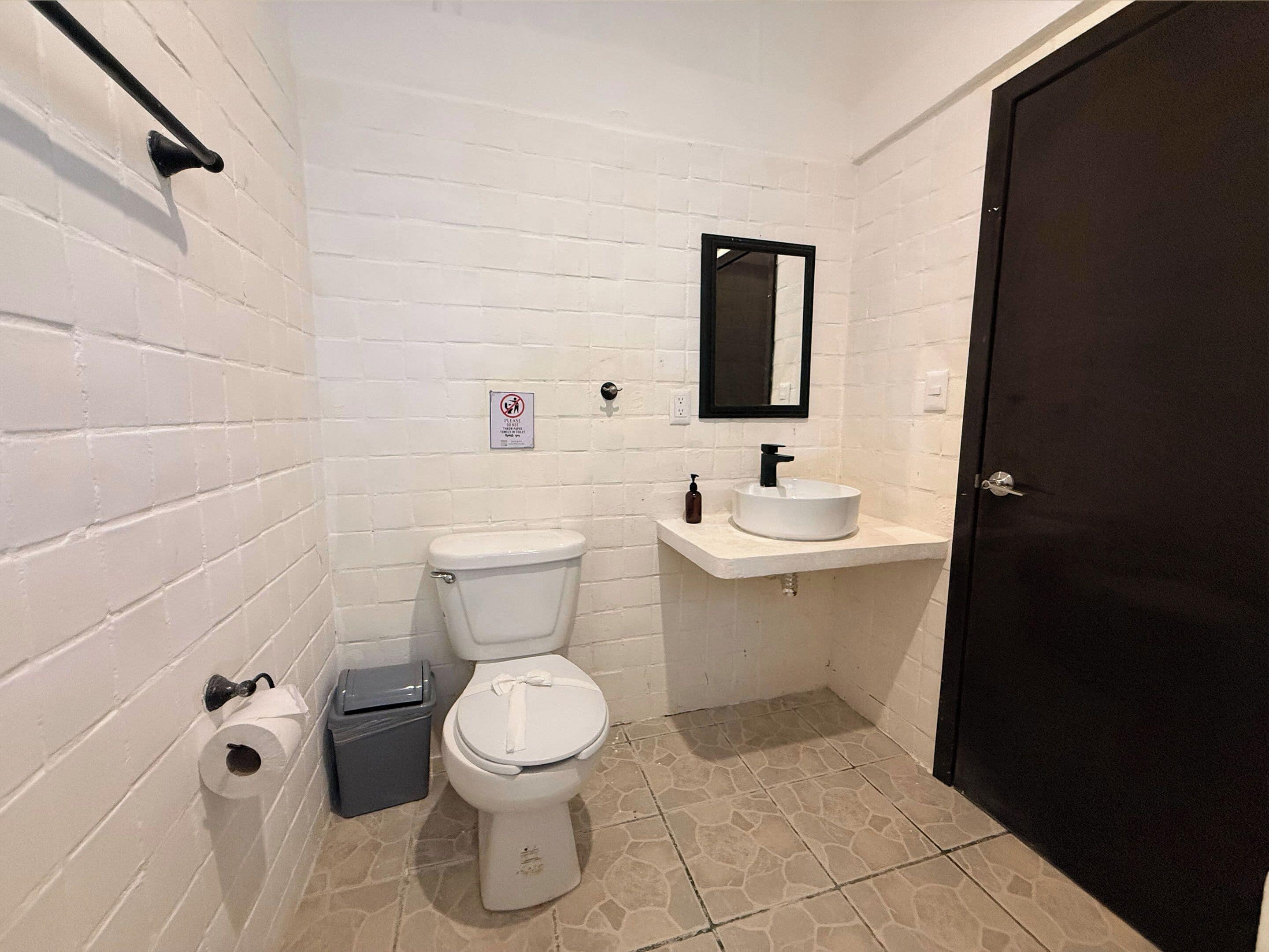 A small, white-walled bathroom with a toilet, a sink, and a mirror.