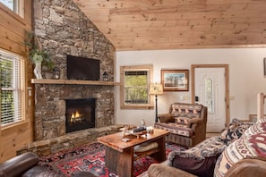 A cozy living room with a stone fireplace, wooden ceiling, and a comfortable seating area. - Peace By The Creek-Hot Tub, Easy Access, Dogs Okay (Maggie Valley)
