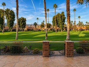 A golf course with a clear view of the fairway, surrounded by palm trees and a brick fence. - Condo in Palm Desert, California (Palm Desert)