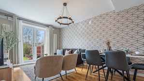 Ett modernt matområde med en vägg som har ett geometriskt mönster, en kristallkrona och utsikt genom stora skjutdörrar.