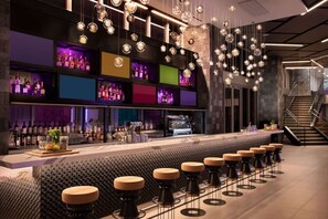 Eine Bar mit einer langen Theke, Hockern und hängenden, kugelförmigen Leuchten.
