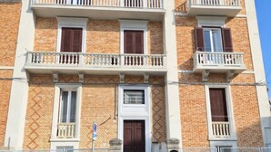 A multi-story building with a brick facade, balconies, and a central entrance with a door. - Elegant apartment in the center of Matera, 200 meters from the entrance to the Sassi (Matera)
