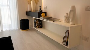 A modern living room with a white console table, a black ottoman, and a black rug. - Elegant apartment in the center of Matera, 200 meters from the entrance to the Sassi (Matera)