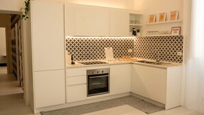 A modern kitchen with white cabinetry, a built-in oven, and a patterned backsplash. - Elegant apartment in the center of Matera, 200 meters from the entrance to the Sassi (Matera)