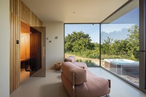 Ein modernes Interieur mit einer Couch, einer Whirlwanne und Blick auf einen Wald.