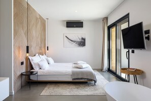 A modern bedroom with a bed, a flat-screen TV, a large window, and a wall-mounted TV. - Luxury 6BR Villa, Heated Infinity Pool, Playground (Pazin)