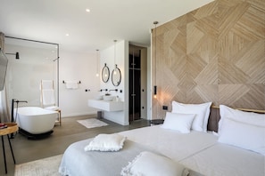 Ein modernes Schlafzimmer mit einem großen Bett, einer gläsernen Dusche, einem Schminktisch mit Waschbecken und einer Wand mit Zickzackmuster.