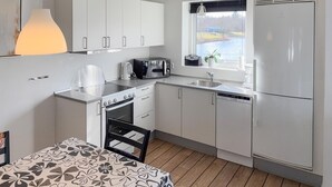 Una cocina compacta con armarios blancos, estufa, microondas y lavavajillas.