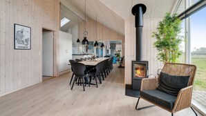 Ett modernt kök med matplats, ett stort fönster och en vedkamin.