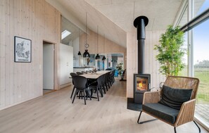 A modern kitchen with a dining area, a large window, and a wood-burning stove. - Nice home in Ringkøbing with sauna (Ringkøbing)
