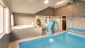 En modern inomhuspool med en vattenrutschkana, ett separat bubbelbad och en duschplats.