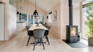 Ett modernt kök med matplats, träpanel på väggarna, en stor spis och utsikt över omgivningarna.