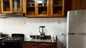 Et køkken med træskabe, en gas komfur, et køleskab og en kaffemaskine.