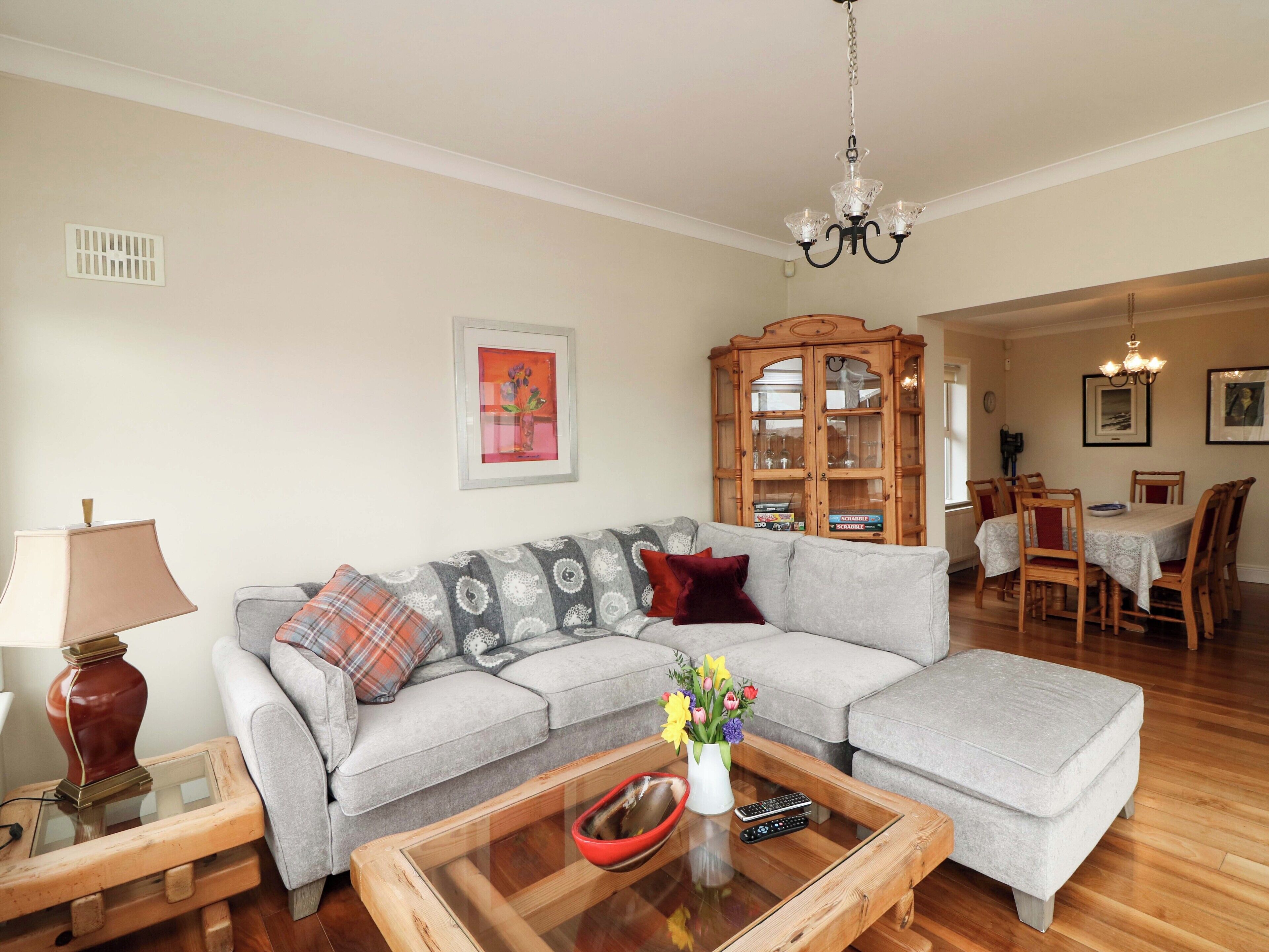 A living room with a sofa, coffee table, and a dining area with chairs and a cabinet.