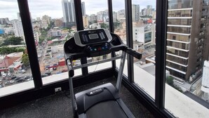 Et fitnesscenter med løbebånd, store vinduer og udsigt over byen.