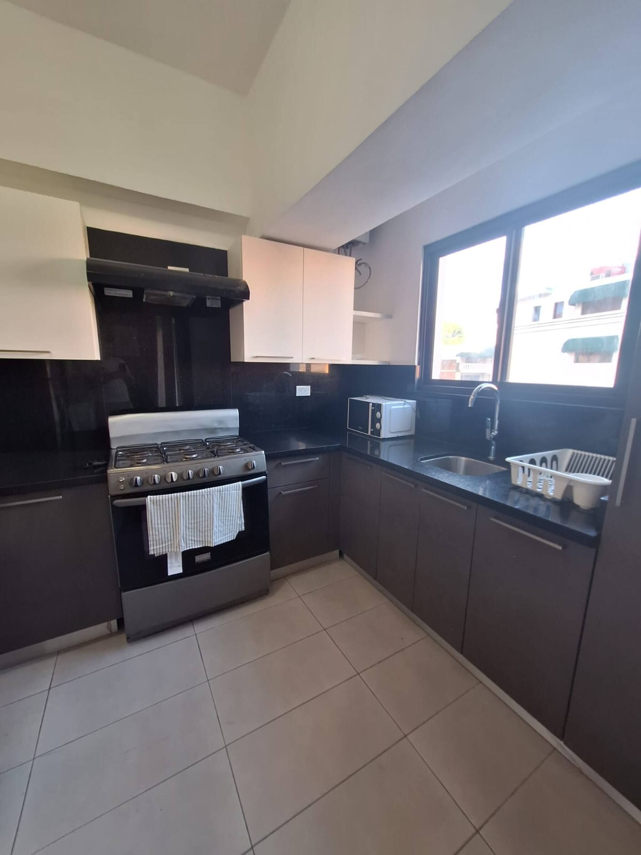 A modern kitchen with a gas stove, oven, and a window with a view of buildings.