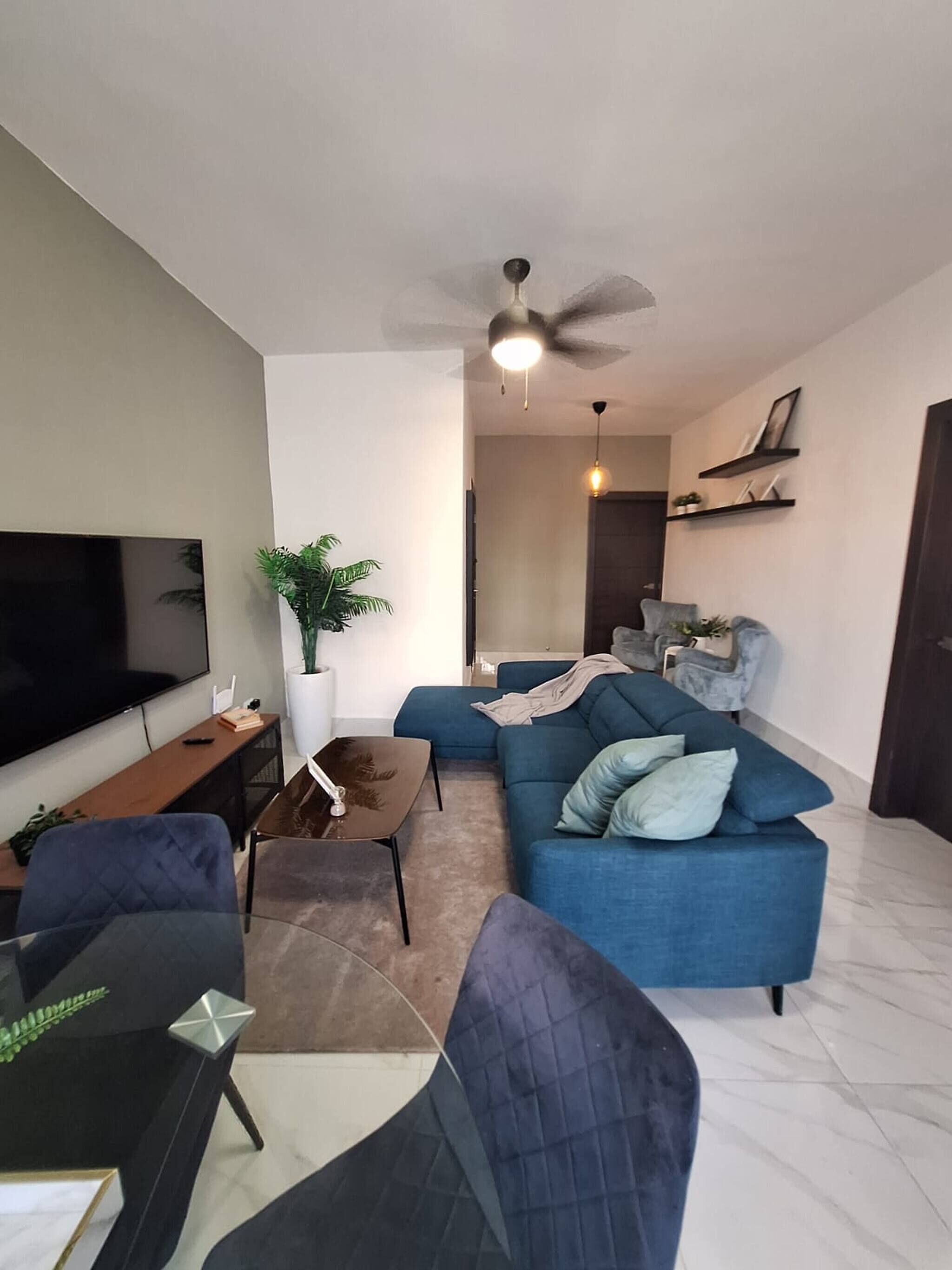 Ein Wohnzimmer mit Fernseher, Sofa, Couchtisch und Deckenventilator.