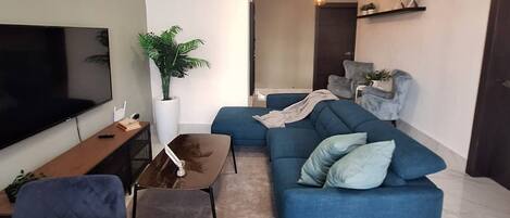 Ein Wohnzimmer mit Fernseher, Sofa, Couchtisch und Deckenventilator.