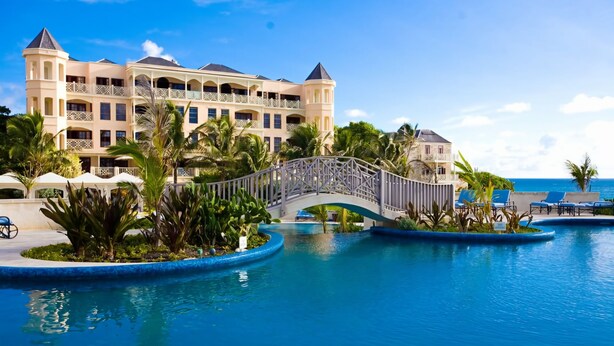 A resort with a large pool, a bridge, and a building with multiple balconies. - A beautifully appointed 2-bdrm, 2-bath resort villa atop Barbados’ most celebrated cliffside, w/ panoramic ocean views & designer interiors. Dedicated concierge service & complimentary airport transfers. (St. Philip)