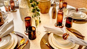 A table set for dining with a vase of green grapes, a large bowl, and multiple glasses of wine. - A beautifully appointed 2-bdrm, 2-bath resort villa atop Barbados’ most celebrated cliffside, w/ panoramic ocean views & designer interiors. Dedicated concierge service & complimentary airport transfers. (St. Philip)