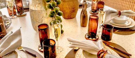 A table set for dining with a vase of green grapes, a large bowl, and multiple glasses of wine.
