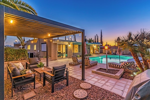 A poolside area with lounge chairs, a pergola, and a swimming pool.