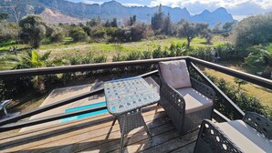 En terrasse med udendørs møbler med udsigt over et bjergrigt landskab.