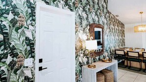 A room with a door, a mirror, a table with chairs, and a patterned wall. - Sleeps 10 • Outdoor Oasis • Heated Pool • Grill (Bradenton)