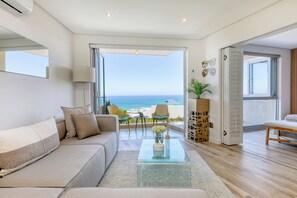 Ein modernes Wohnzimmer mit einem Glastisch, einer Couch und Blick auf den Ozean.