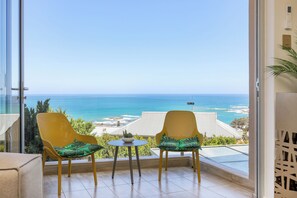 Ein Balkon mit zwei Korbstühlen, einem kleinen Tisch und Blick aufs Meer.