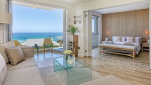 Un soggiorno moderno con un tavolino in vetro, un divano, un letto e vista sull'oceano.