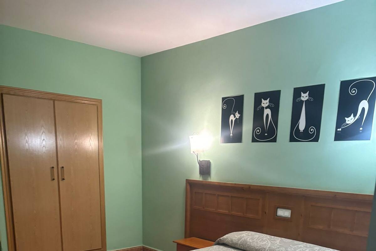 Un dormitorio con cama, armario, mesita de noche y decoración en la pared.